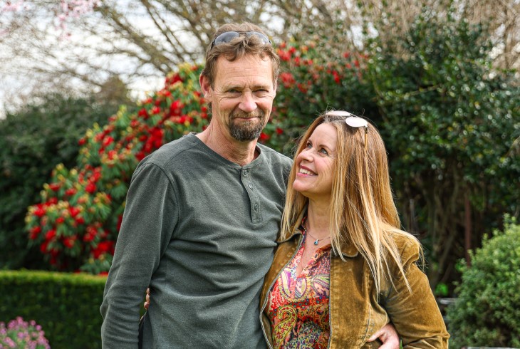 Mandy and her husband smile for a photo in their garden