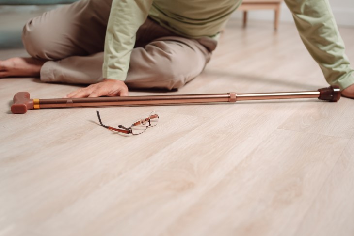 Older person who has fallen over, sitting on the floor.