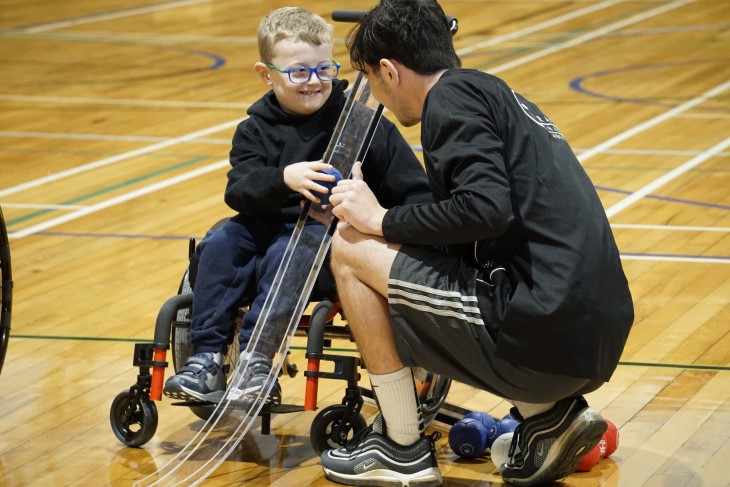 A coach teaching a young disabled boy a skill. 