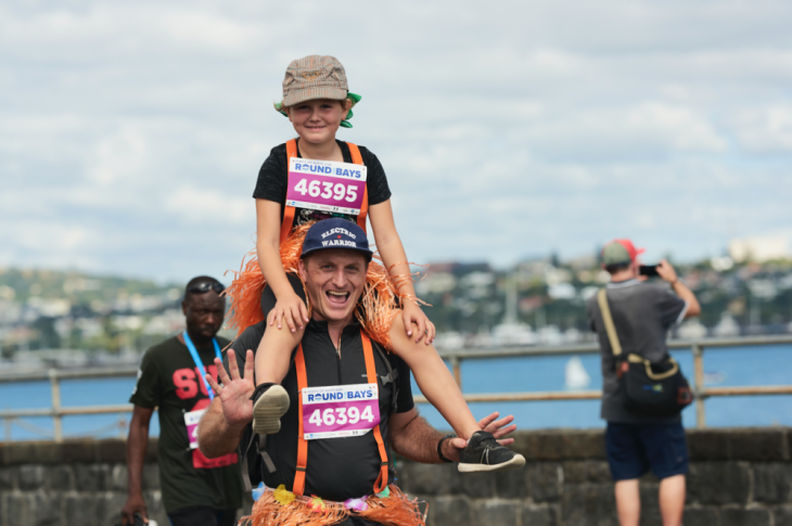 Dad holds child on his shoulders, both wearing orange suspenders