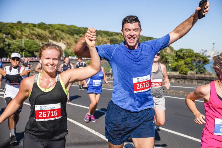 Two runners drenched in sweat put their arms up and cheer