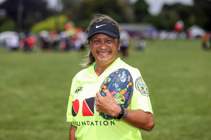 Tina smiles while holding a rugby ball in her referee gear