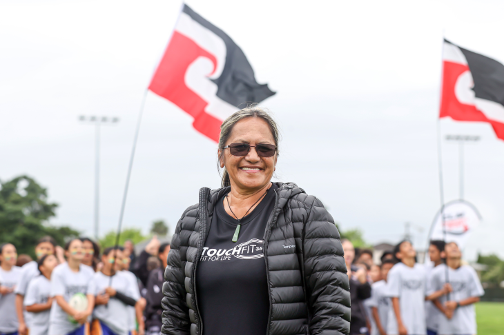 Tina smiles for the camera with Maori flags flying in the background