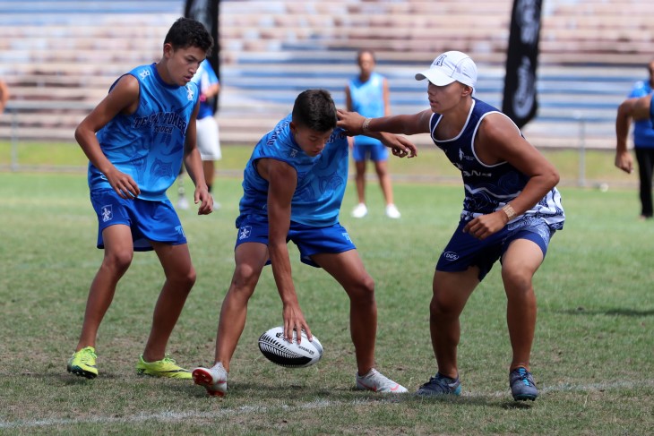 Several men playing touch rugby on a field.