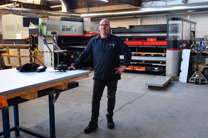 Adrian Reid standing next to a table in the factory he works at. 