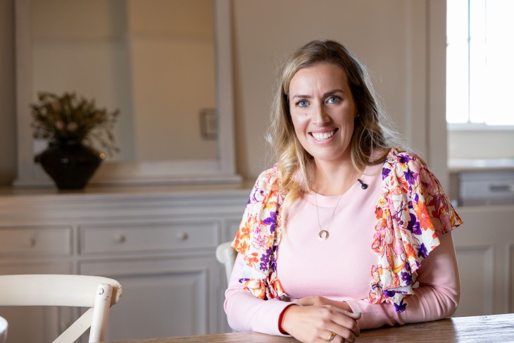 A portrait photo of Alicia Mabey sitting at her kitchen table and smiling.