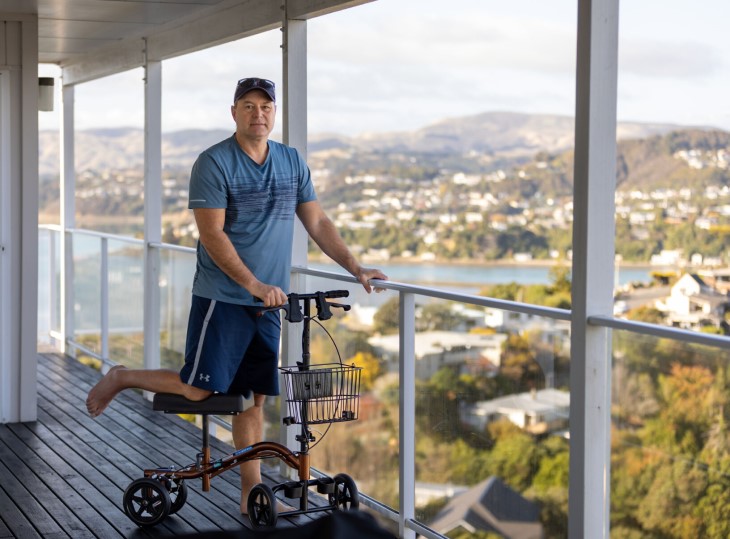 Andy Pedley using a knee scooter to stand on his deck at home. 