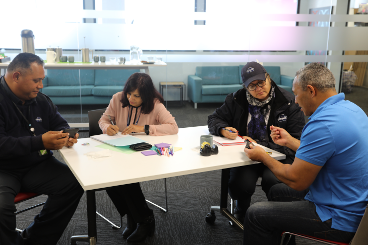Several Armourguard employees sitting at a desk working on a task during a workshop.