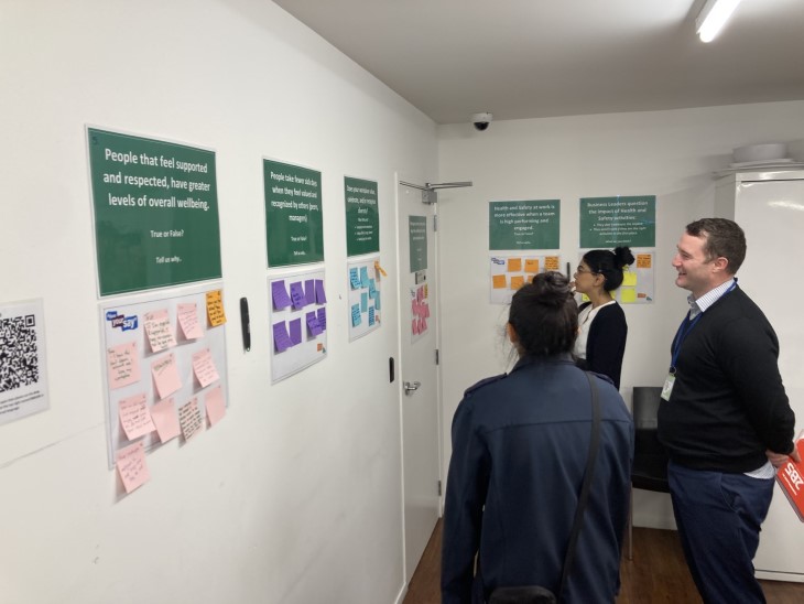 Several Armourguard employees looking at post-it notes on the wall during a workshop.