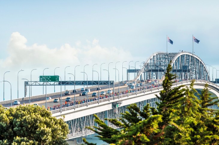 A long-distance shot of a large group of people running over the Auckland Harbour Bridge during the Auckland Marathon.