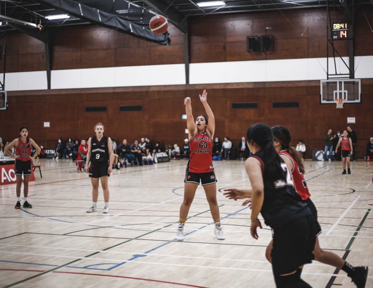 A young female basketball player shoots at the hoop.