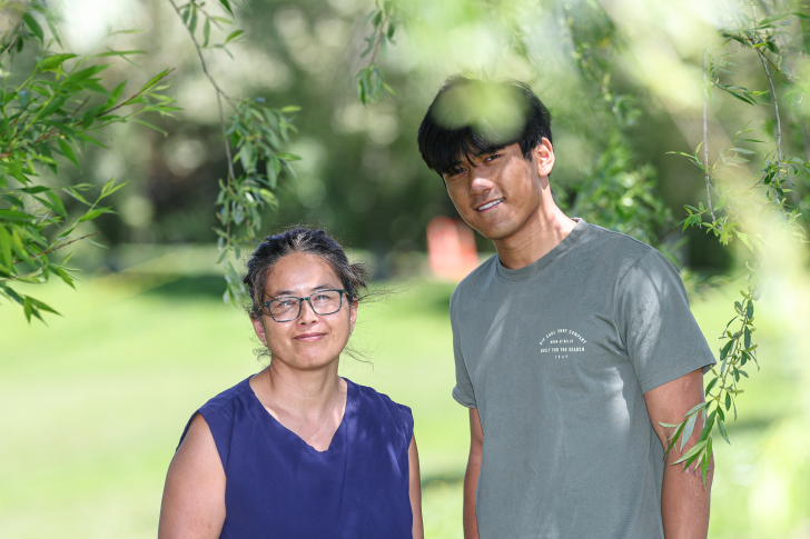 A portrait photo of Borynt Em Ream standing under a tree with mum Soriya.