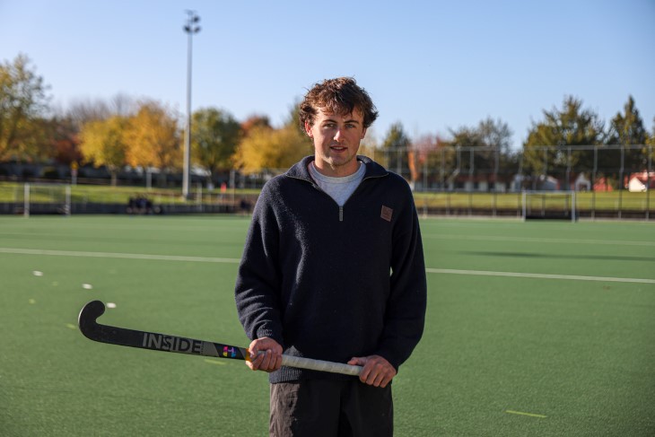 Campbell Gray standing on a hockey turf and holding his hockey stick in both hands.