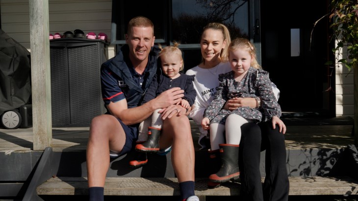 Carl Perry sitting on the porch of his house with his wife and two of his daughters.