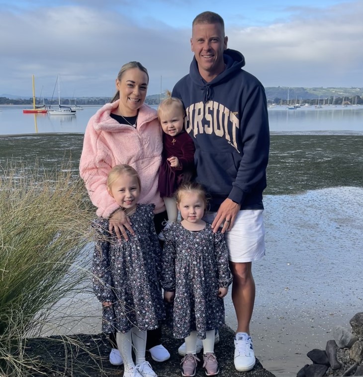 Carl Perry posing for a family photo with his wife and three daughters. 