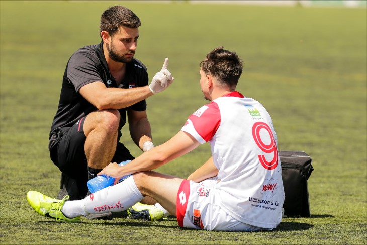 A football player being tested for concussion on the field by a medical professional. 