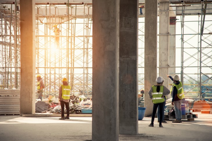 Workers talking inside a building that's being constructed.