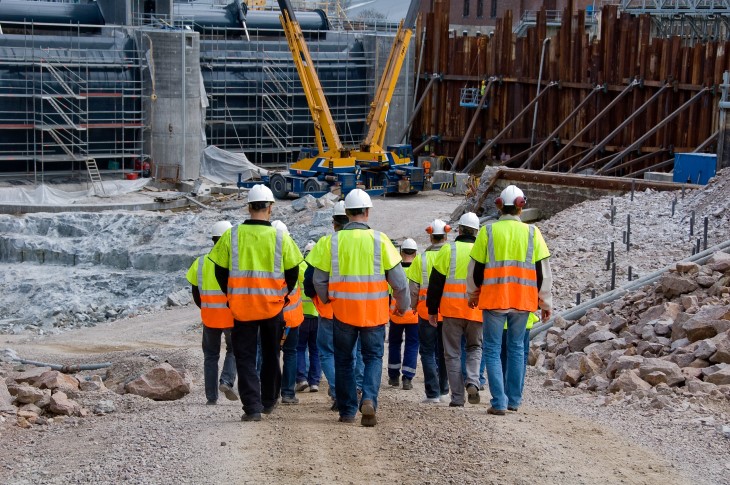 A group of construction workers walking into a building site. 