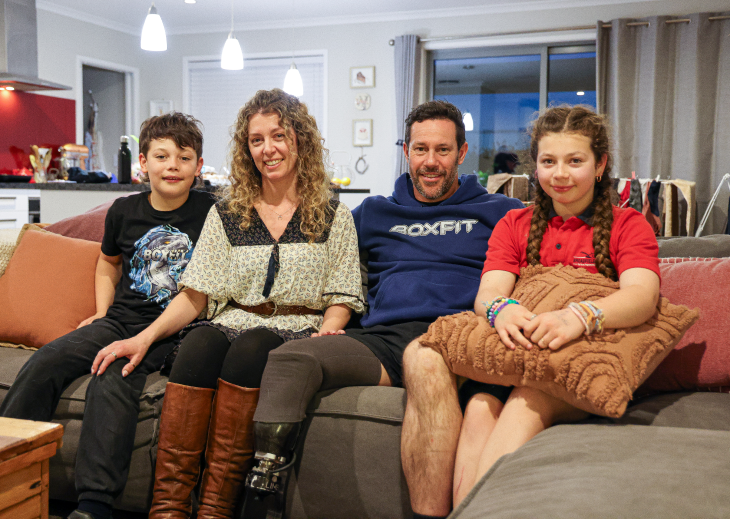 Craig Harrington sitting on a couch at home with his wife and two children.
