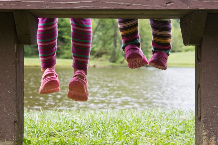 children sitting on seat wearing pink crocs