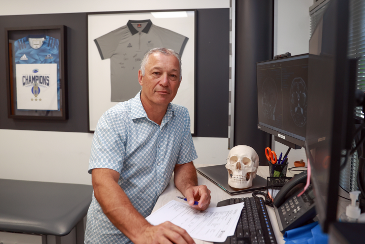 Dr Stephen Kara sitting at his desk in a medical practice and looking at the camera. 