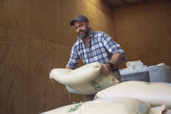 Farmer Jon Pemberton lifting a sack in a shed.