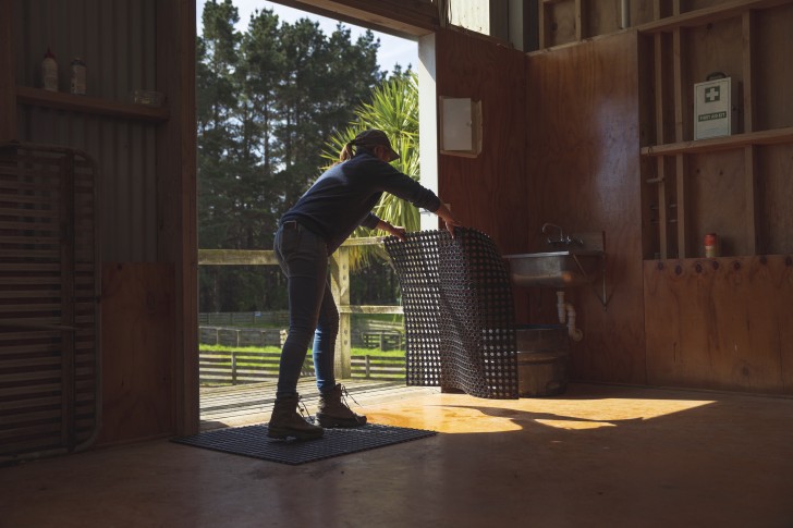 Farmer Emma Crutchley laying down mats in a shed.