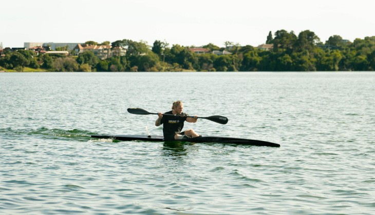 Finn Murphy rowing in his canoe on a lake.