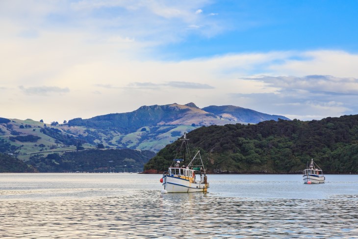 A pair of fishing boats in a harbour heading out to sea. 