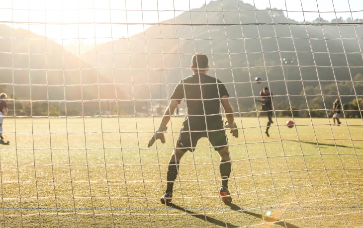 A football goalkeeper about to save a shot at goal. 