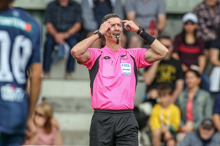 A football referee signalling he's stopping play because of a head injury.