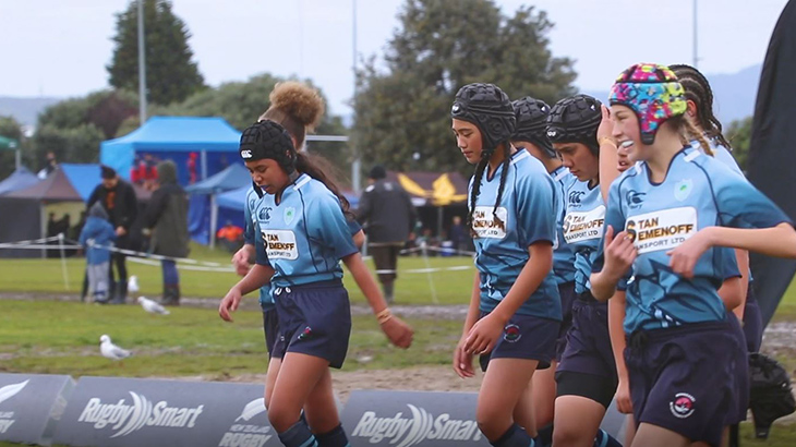 Members of a girls rugby team walking together on the field. 