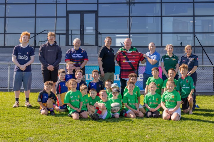 A group photo showing a children's rugby team and adult members of the South Canterbury rugby community.