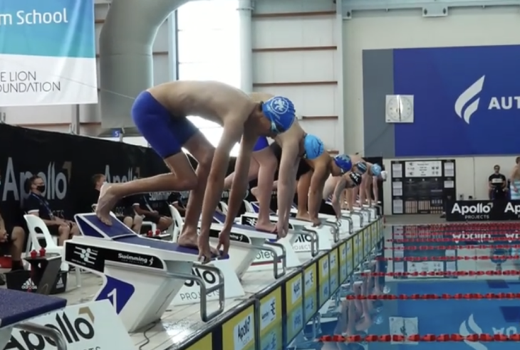 Guy Harrison and a line of swimmers about to jump into the pool at the start of a race. 