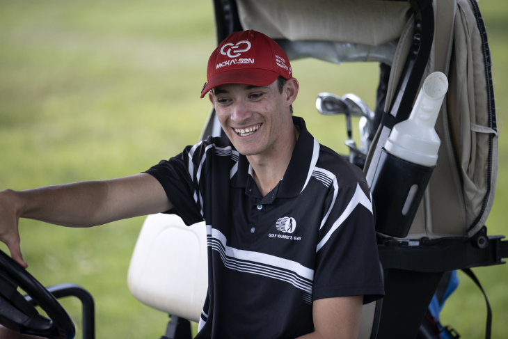 Guy Harrison sitting on a golf cart and smiling. 