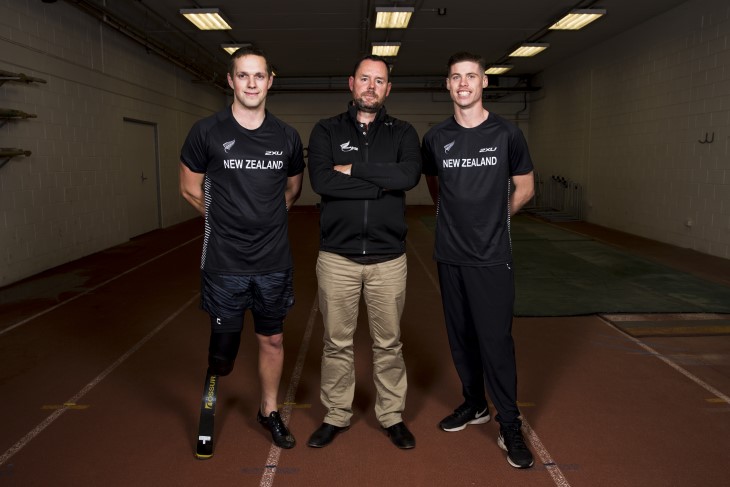 Hamish Meacheam standing with a pair of Para athletes he coaches. 