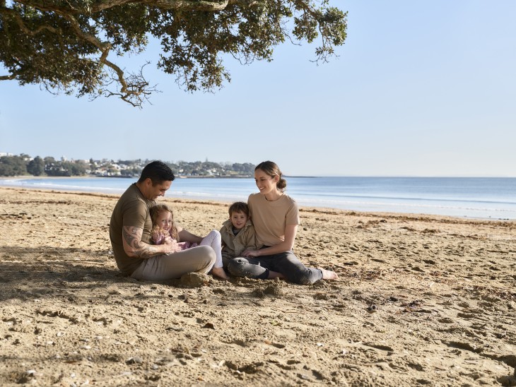 A young family sitting on the beach on a sunny day.