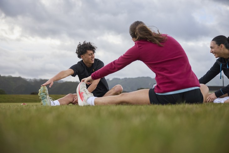 Several sports people doing stretches on a field.