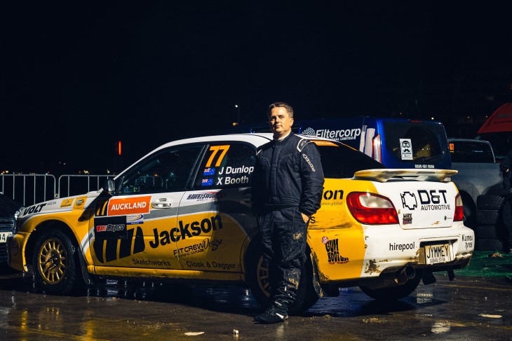 James Dunlop standing in front of his rally car and looking at the camera. 