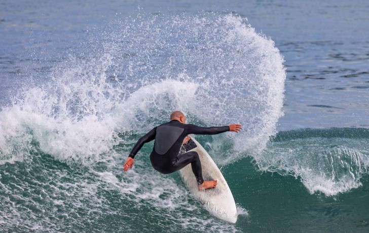 James Whitaker photographed from behind surfing a wave.