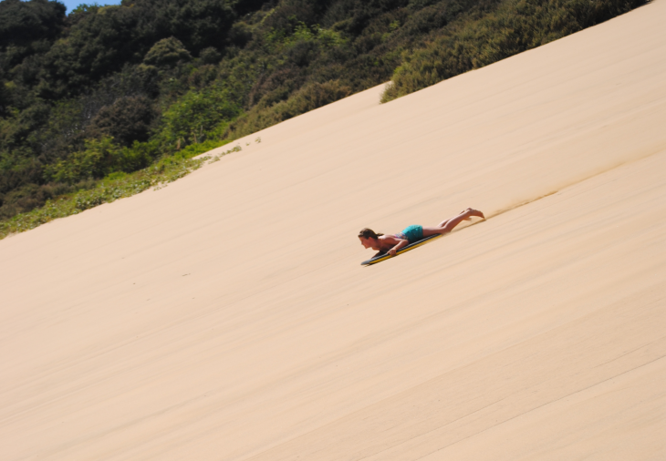 Jamie Astwood sliding down a dune on her boogie board. 