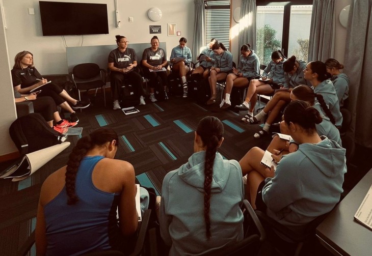 Jo Morrison in a room with a netball team taking them through a theory session.