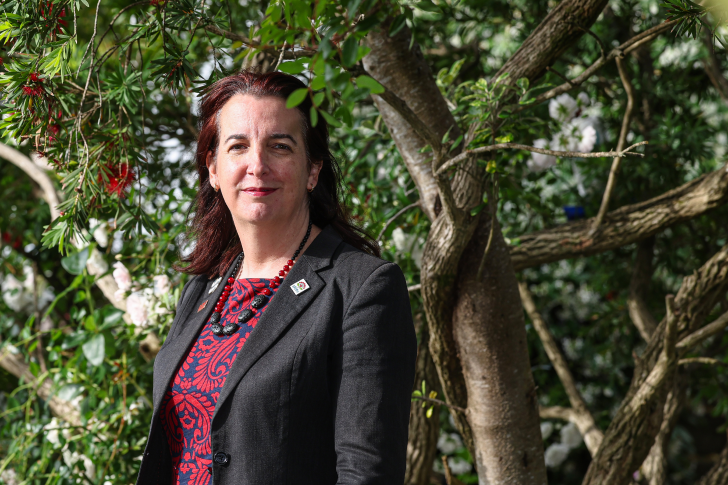 A portrait photo of Julie Fairey standing in front of a tree.