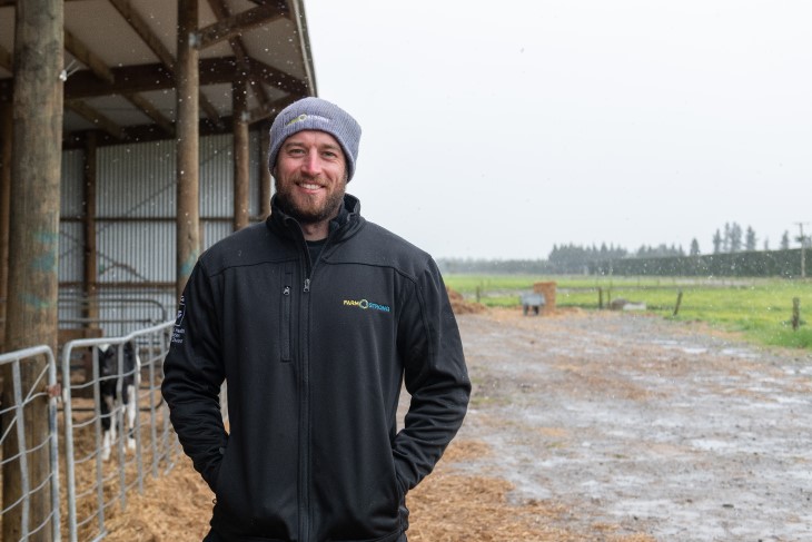 Dairy farmer Kane Brisco standing on his farm and smiling. 
