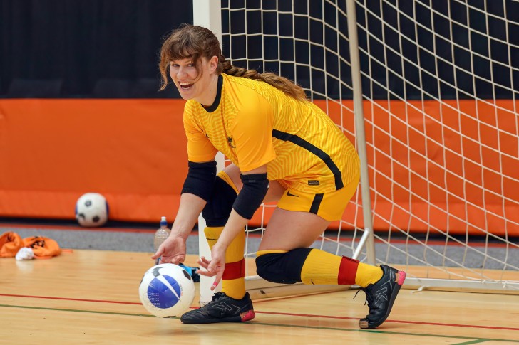 MacKenzie Falco rolling the ball out with her hands during a futsal game.