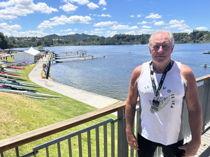 mike hickson Mike Hickson standing on the edge of Lake Karāpiro with a line of waka ama canoes on the grass.