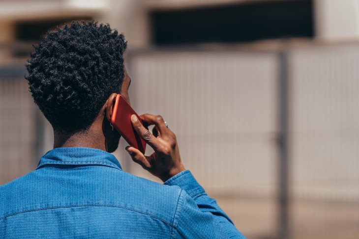 A man shown from behind talking on a mobile phone. 