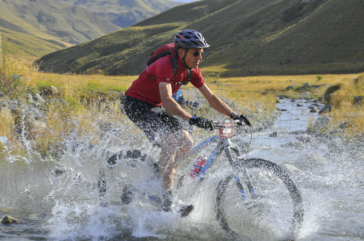 mountain bike water A male mountain biker riding through the water of a shallow river.