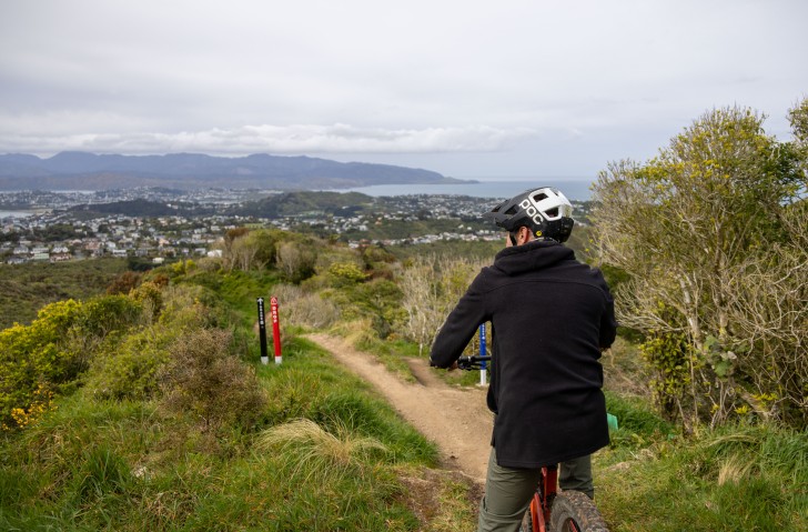 A man shown from behind riding down a mountain bike track.