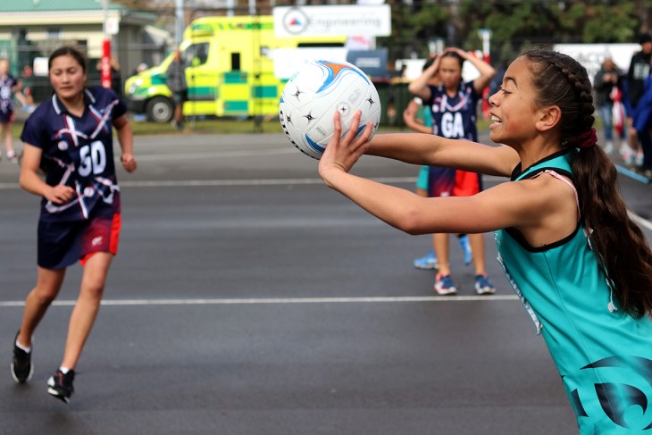 A young netball player passes the ball. 